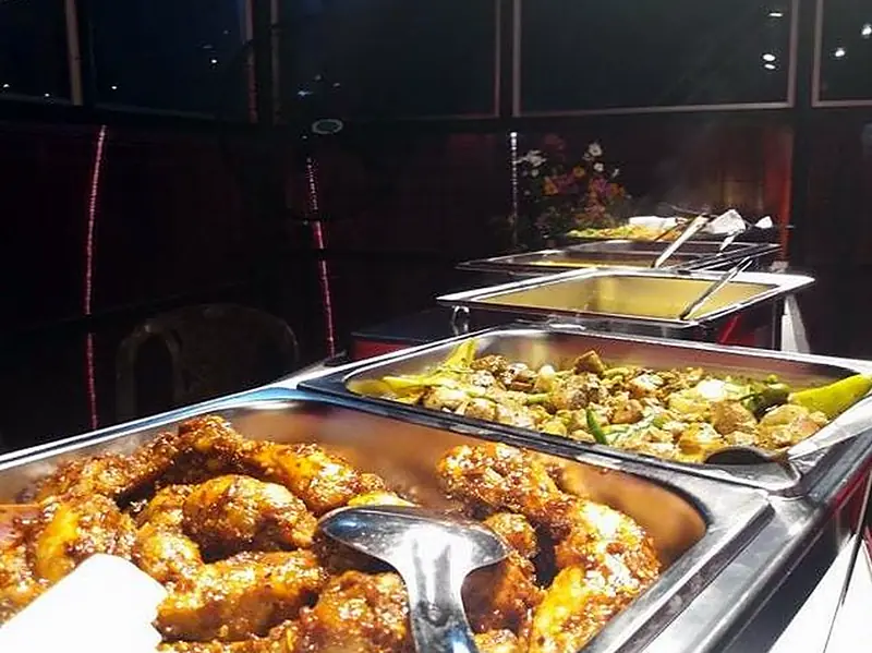 Hot buffet trays of devilled chicken and vegetables under the lights at Restaurant Two