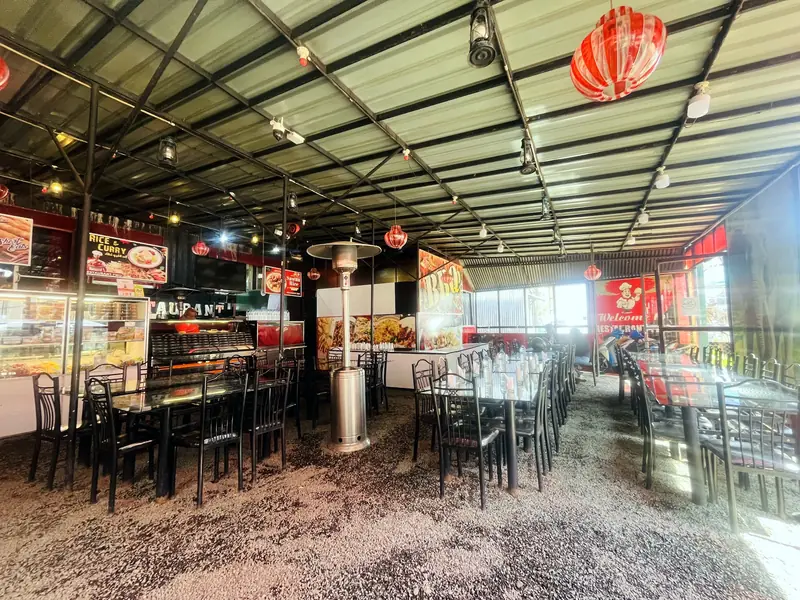 The covered dining hall at Restaurant Two, with long tables, red lanterns and the open kitchen counter
