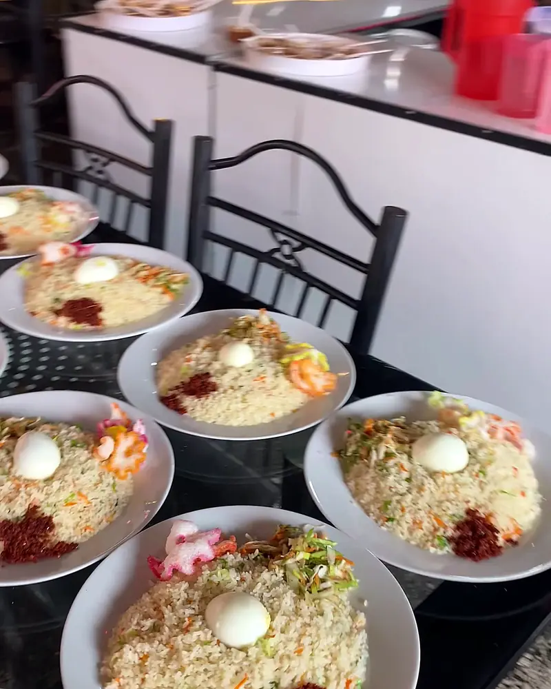 Plates of fried rice with egg and chilli paste lined up on the counter, ready to serve