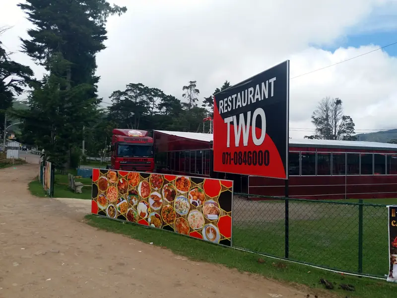 The big red Restaurant Two sign and food banner beside the road, with the dining cars behind